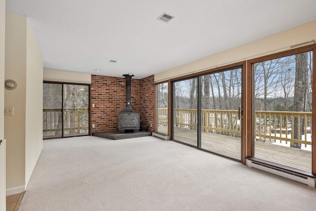 unfurnished living room featuring a wood stove, carpet floors, and a baseboard radiator