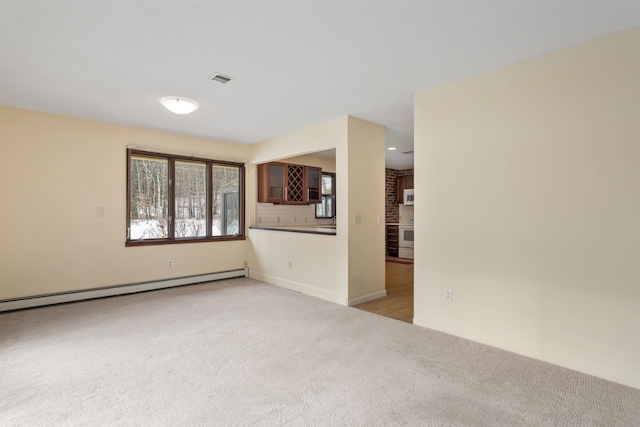 spare room featuring light carpet and baseboard heating