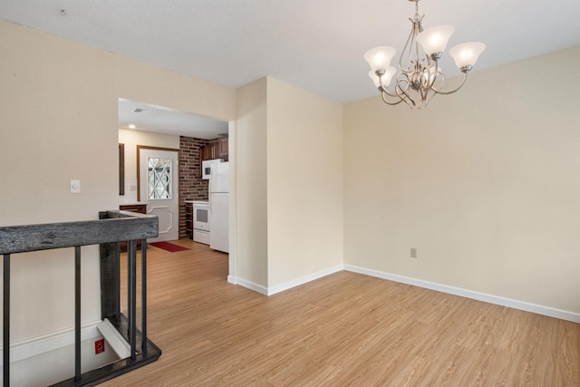 empty room featuring light hardwood / wood-style flooring and a notable chandelier