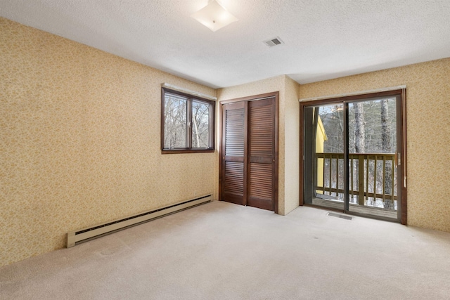 unfurnished bedroom featuring a baseboard radiator, a textured ceiling, light carpet, access to exterior, and a closet