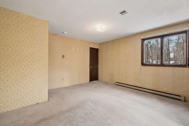 carpeted empty room featuring a baseboard heating unit