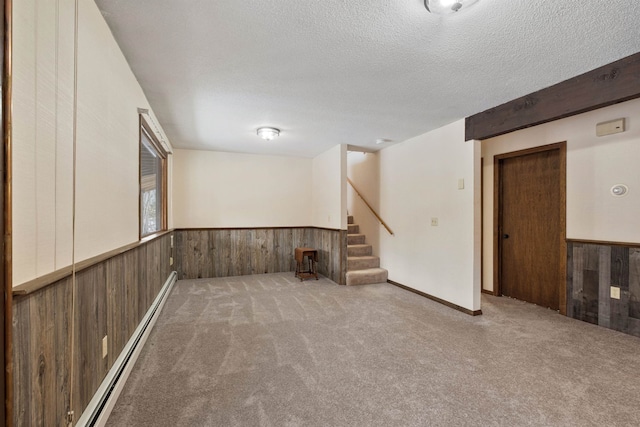 basement with carpet, a baseboard heating unit, and a textured ceiling