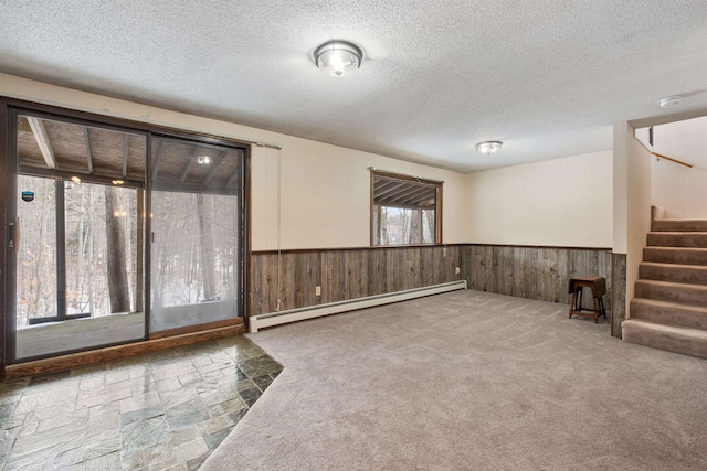 spare room featuring a textured ceiling, baseboard heating, and carpet floors