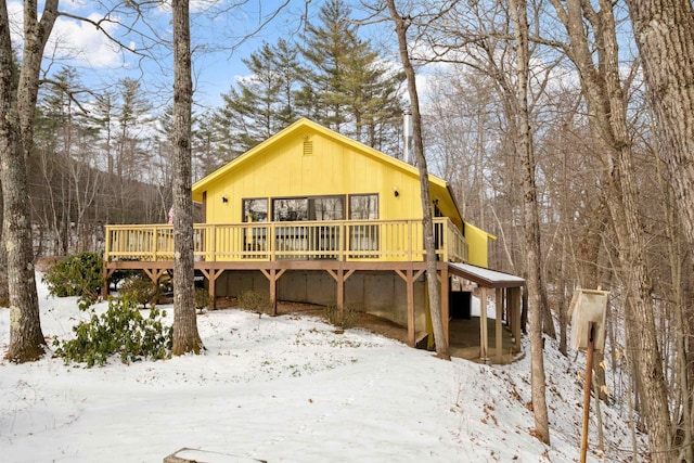 snow covered house featuring a wooden deck