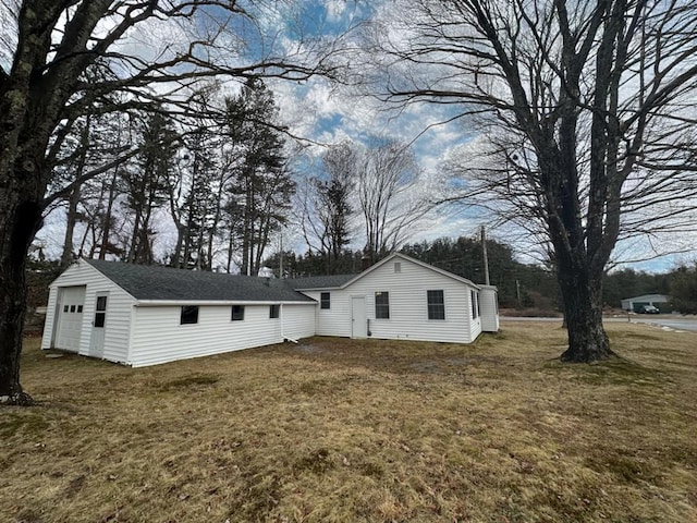 view of side of property with a garage, a lawn, and an outdoor structure