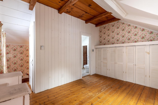 unfurnished bedroom with connected bathroom, a closet, light wood-type flooring, wooden ceiling, and beam ceiling