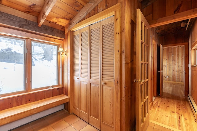 hall featuring wood ceiling, light tile patterned floors, lofted ceiling, and wooden walls