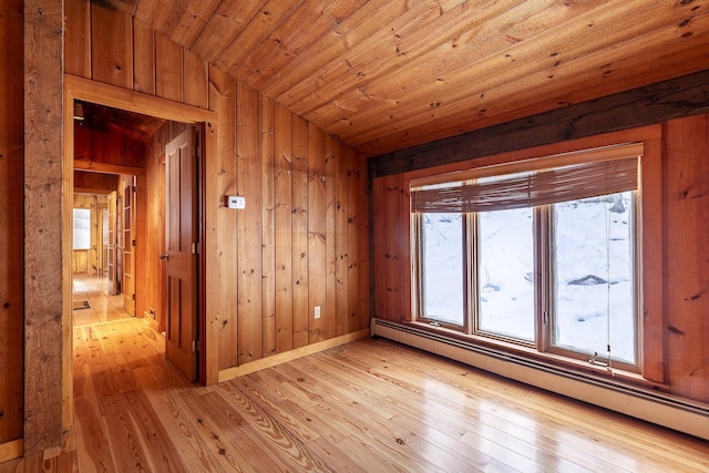 empty room with baseboard heating, lofted ceiling, wood ceiling, wooden walls, and light hardwood / wood-style flooring