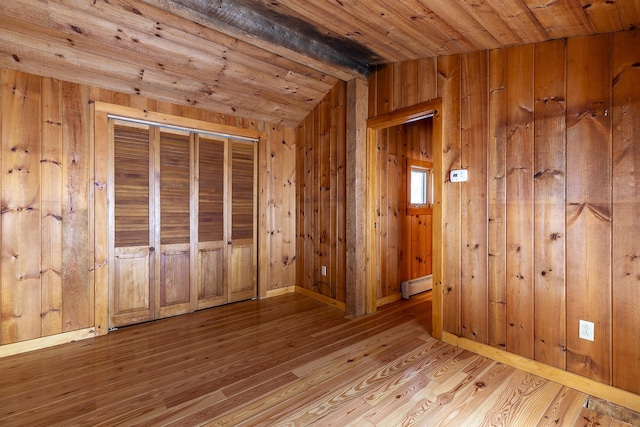 interior space featuring a baseboard radiator, wood ceiling, wood walls, light wood-type flooring, and beam ceiling