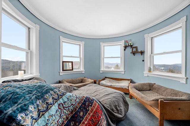 carpeted bedroom with a mountain view, multiple windows, and crown molding