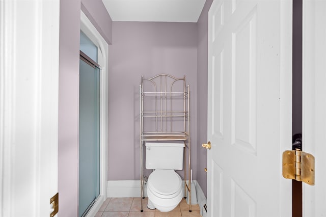 bathroom featuring a shower with shower door, tile patterned floors, and toilet