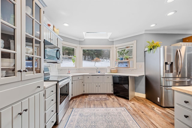 kitchen with sink, appliances with stainless steel finishes, plenty of natural light, and light hardwood / wood-style flooring