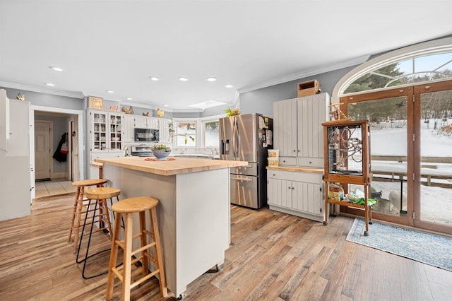 kitchen with crown molding, white cabinets, stainless steel fridge, and a center island