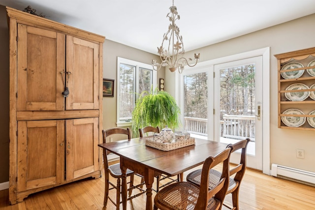 dining space featuring baseboard heating, a notable chandelier, and light hardwood / wood-style floors