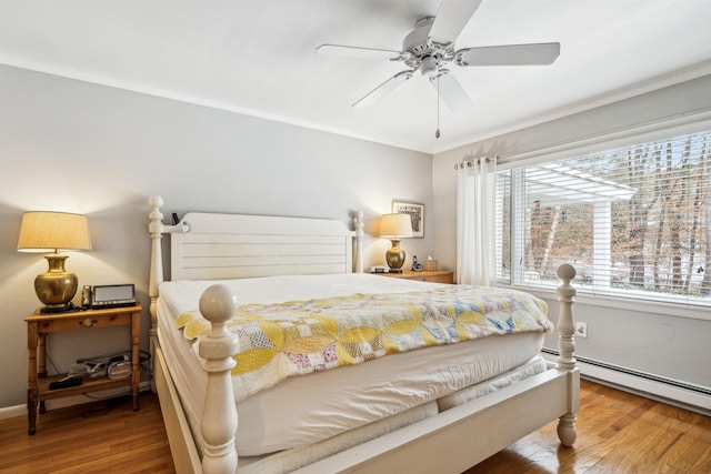 bedroom with ceiling fan, baseboard heating, ornamental molding, and hardwood / wood-style floors