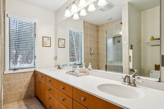 bathroom featuring toilet, vanity, tile walls, tile patterned flooring, and tiled shower