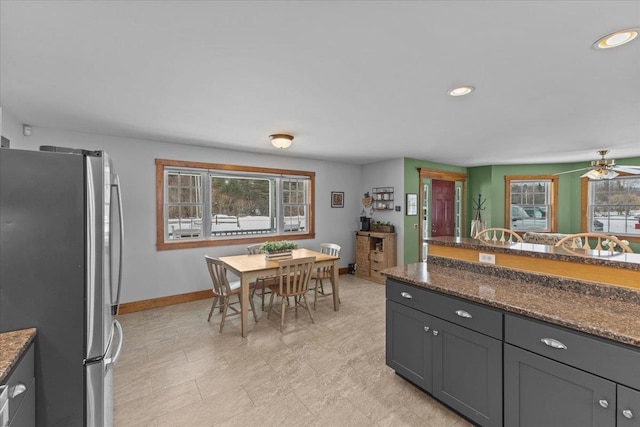 kitchen featuring plenty of natural light, dark stone countertops, and stainless steel fridge