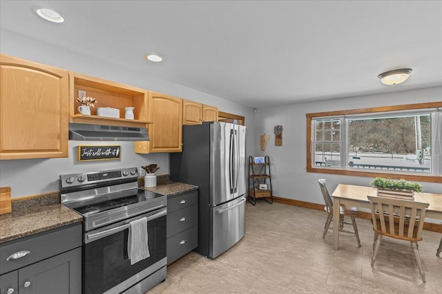 kitchen with light brown cabinets, stainless steel appliances, exhaust hood, and dark stone countertops