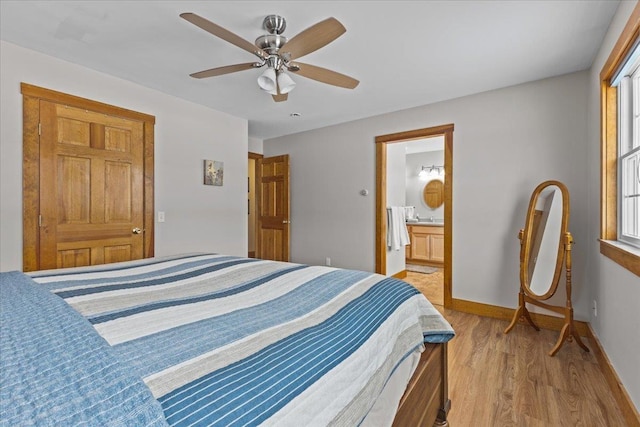 bedroom featuring ceiling fan, ensuite bath, multiple windows, and light hardwood / wood-style flooring