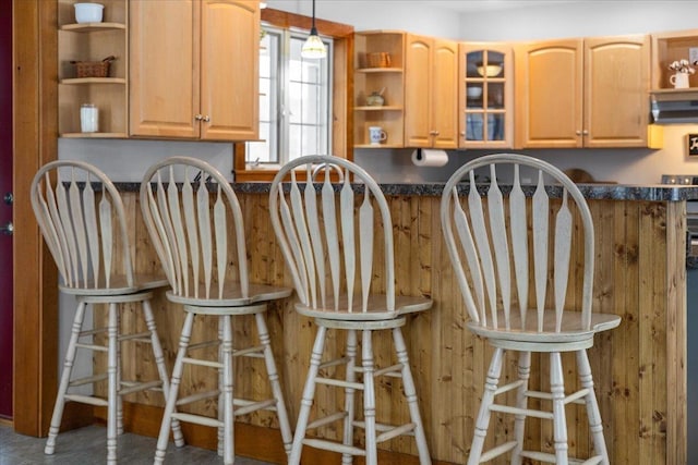 kitchen with a kitchen breakfast bar, hanging light fixtures, and range hood