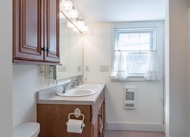 bathroom with heating unit, toilet, and vanity