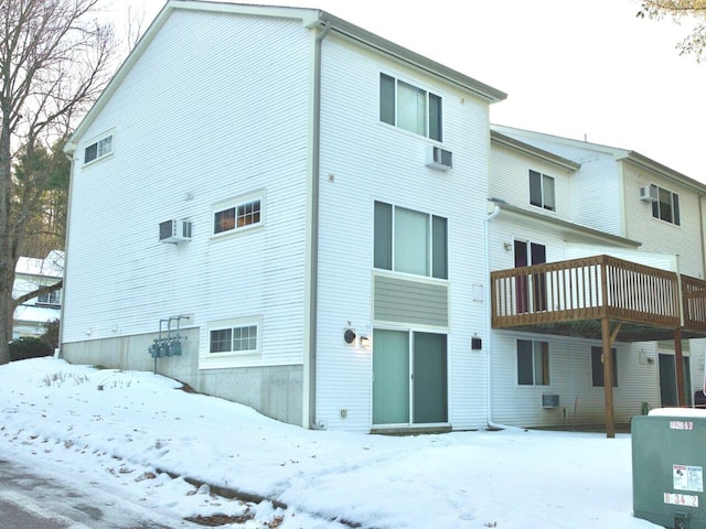 snow covered property with a wall mounted AC