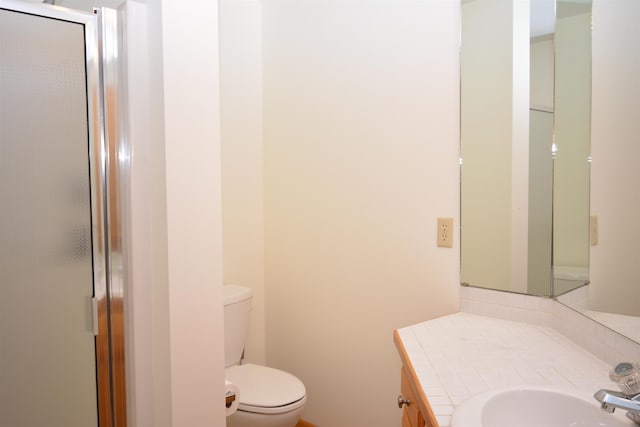 bathroom featuring a shower with shower door, toilet, and vanity