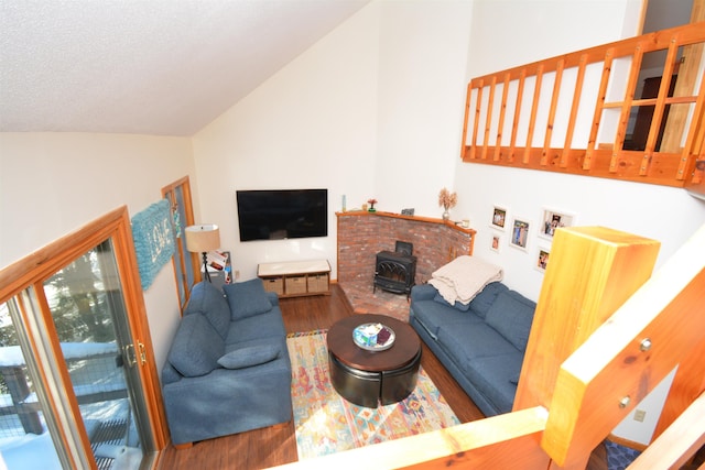 living room featuring lofted ceiling, a textured ceiling, a wood stove, and hardwood / wood-style flooring