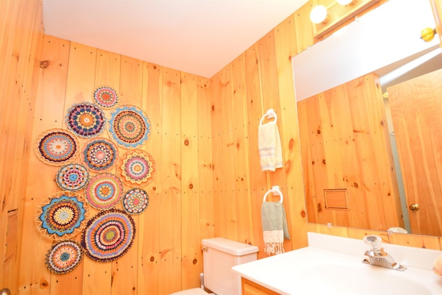 bathroom featuring vanity, toilet, and wooden walls