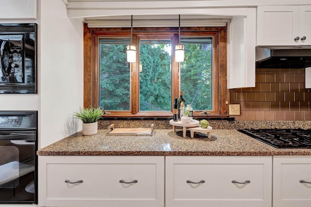 details featuring black appliances, decorative light fixtures, white cabinets, and wall chimney exhaust hood