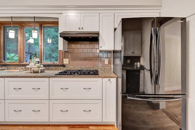 kitchen featuring extractor fan, gas stovetop, white cabinetry, hanging light fixtures, and fridge