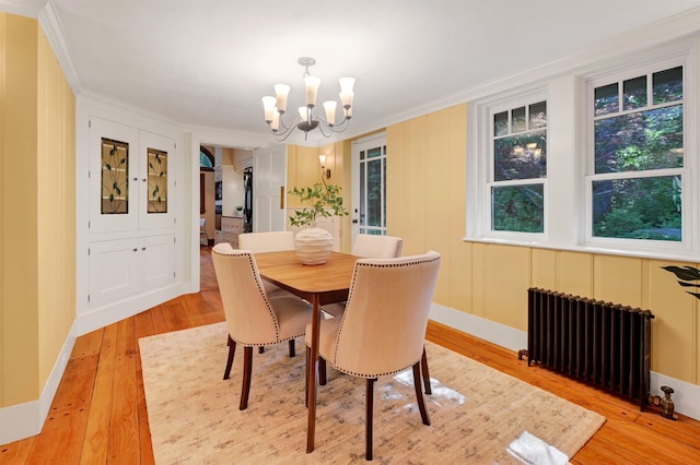 dining room featuring ornamental molding, radiator heating unit, a notable chandelier, and light hardwood / wood-style floors