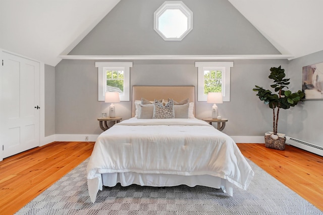 bedroom with a baseboard radiator, vaulted ceiling, and hardwood / wood-style floors