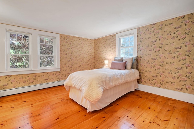 bedroom featuring wood-type flooring, ornamental molding, and a baseboard radiator