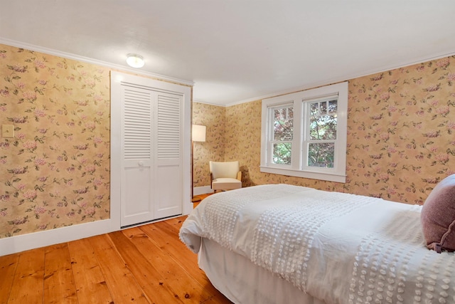 bedroom with hardwood / wood-style flooring, crown molding, and a closet