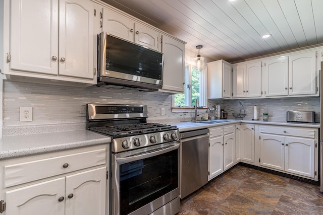 kitchen with backsplash, pendant lighting, sink, white cabinetry, and stainless steel appliances