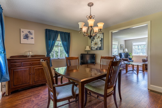 dining area with dark wood-type flooring, a textured ceiling, and a chandelier