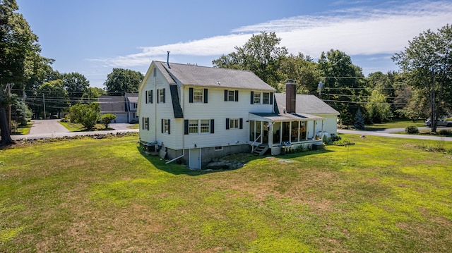 back of property with a sunroom and a lawn