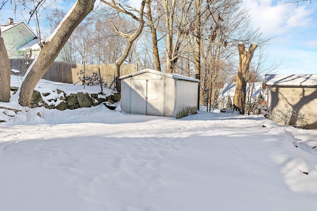 snowy yard featuring a storage shed