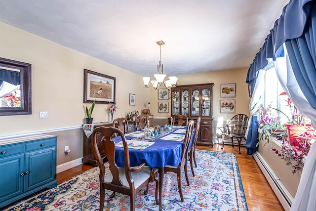 dining space featuring hardwood / wood-style flooring, a baseboard radiator, and a notable chandelier