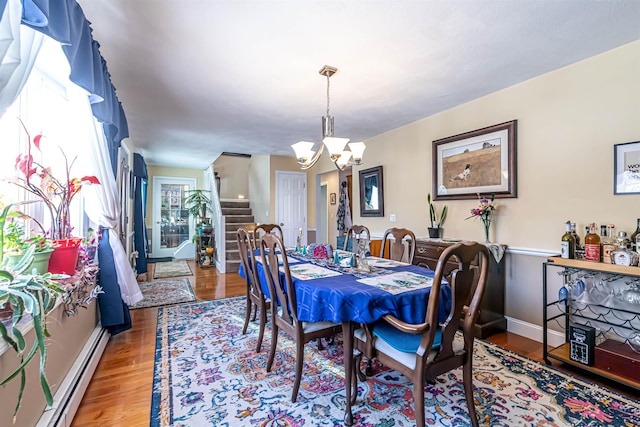 dining space featuring a baseboard radiator, hardwood / wood-style floors, and a notable chandelier