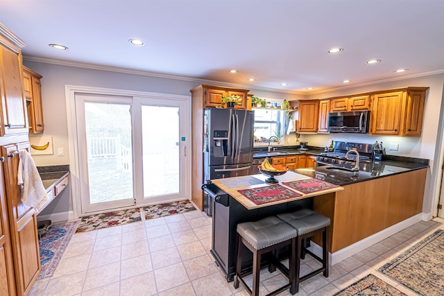 kitchen featuring kitchen peninsula, a kitchen bar, sink, crown molding, and appliances with stainless steel finishes