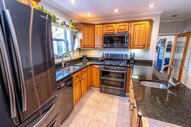 kitchen featuring appliances with stainless steel finishes, dark stone countertops, ornamental molding, and sink