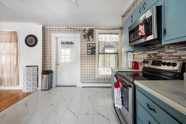 kitchen featuring a baseboard heating unit, stainless steel appliances, tasteful backsplash, blue cabinets, and crown molding