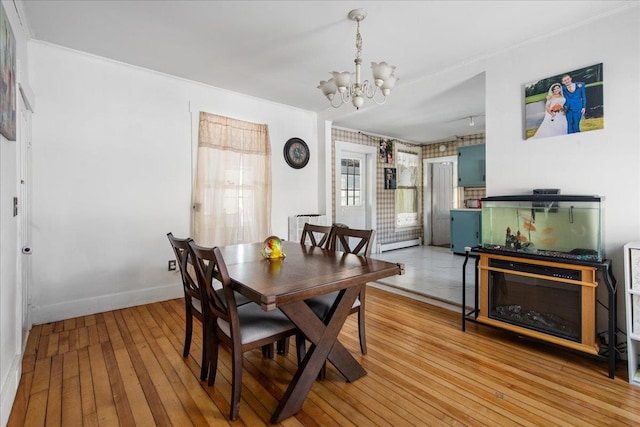 dining room with light hardwood / wood-style floors, a baseboard radiator, and a notable chandelier