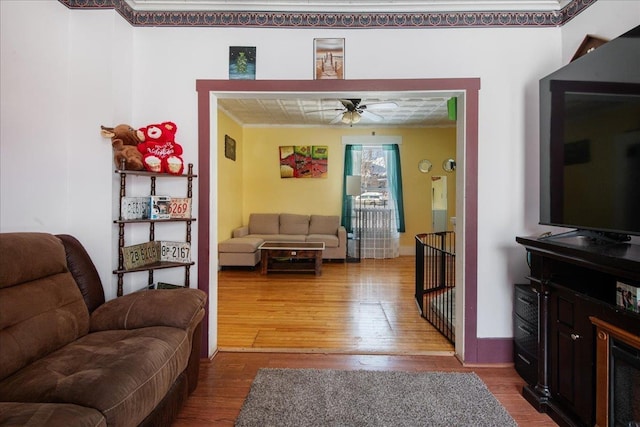 living room with ceiling fan, wood-type flooring, and ornamental molding