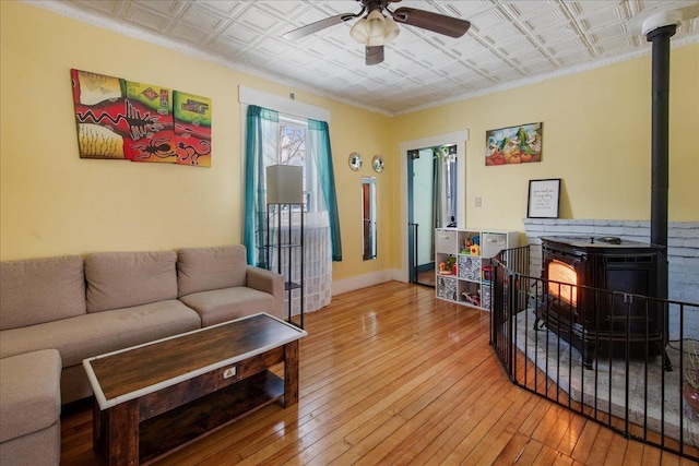 living room featuring ceiling fan, a wood stove, and wood-type flooring