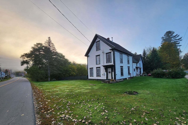 property exterior at dusk featuring a yard