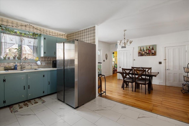 kitchen featuring tasteful backsplash, light wood-type flooring, stainless steel refrigerator, a chandelier, and sink