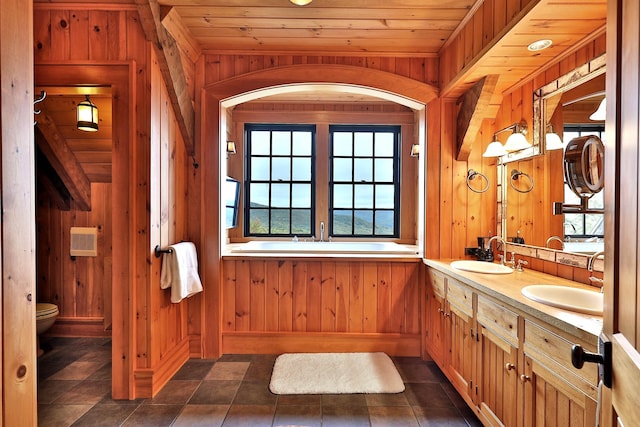 bathroom with vanity, wooden walls, a bathtub, toilet, and wooden ceiling